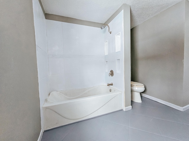 bathroom with toilet, bathing tub / shower combination, tile patterned floors, and a textured ceiling