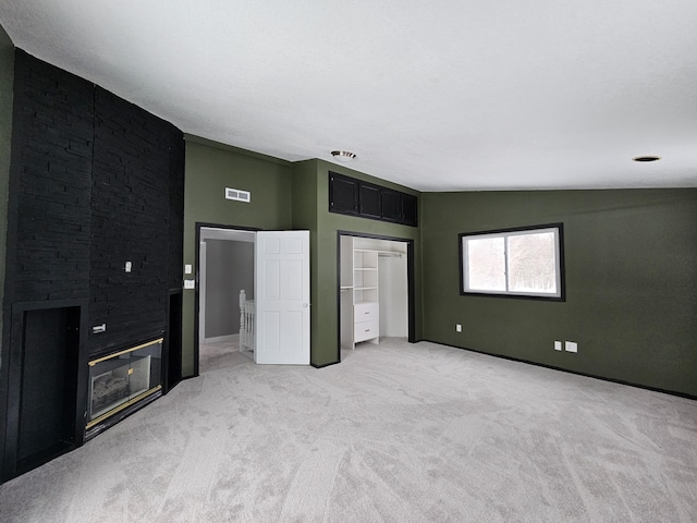 unfurnished bedroom featuring light colored carpet, lofted ceiling, and a fireplace