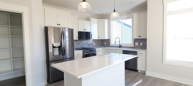 kitchen featuring sink, hanging light fixtures, stainless steel appliances, white cabinets, and a kitchen island