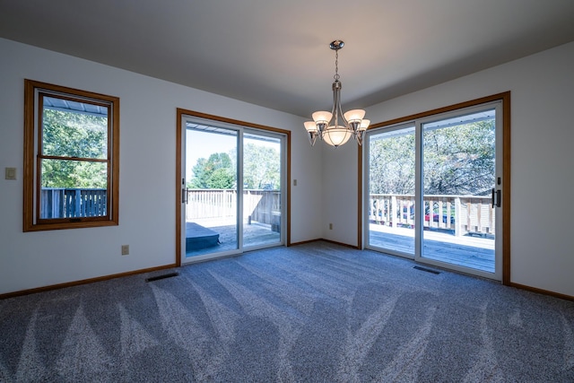 spare room featuring an inviting chandelier and carpet floors