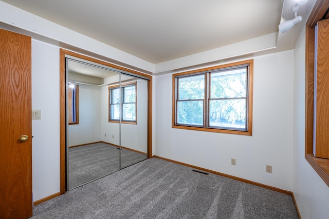 unfurnished bedroom with carpet, a closet, and multiple windows