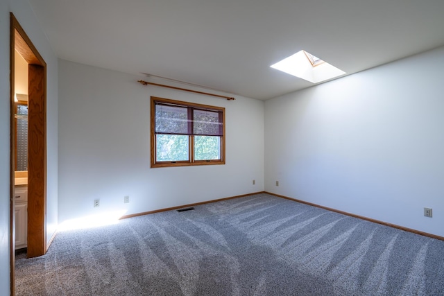 carpeted spare room featuring a skylight