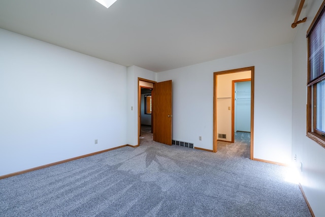 unfurnished bedroom with a walk in closet and carpet floors