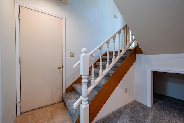 staircase featuring lofted ceiling and carpet