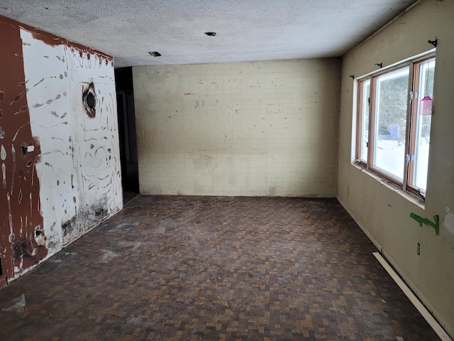 carpeted empty room featuring a textured ceiling, brick wall, and a baseboard radiator