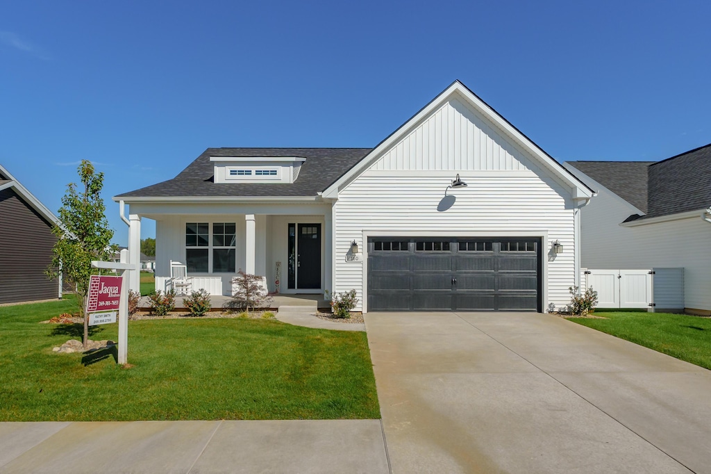 view of front of house featuring a front lawn, a garage, and a porch