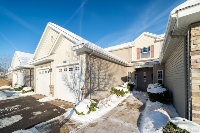 snow covered property with a garage