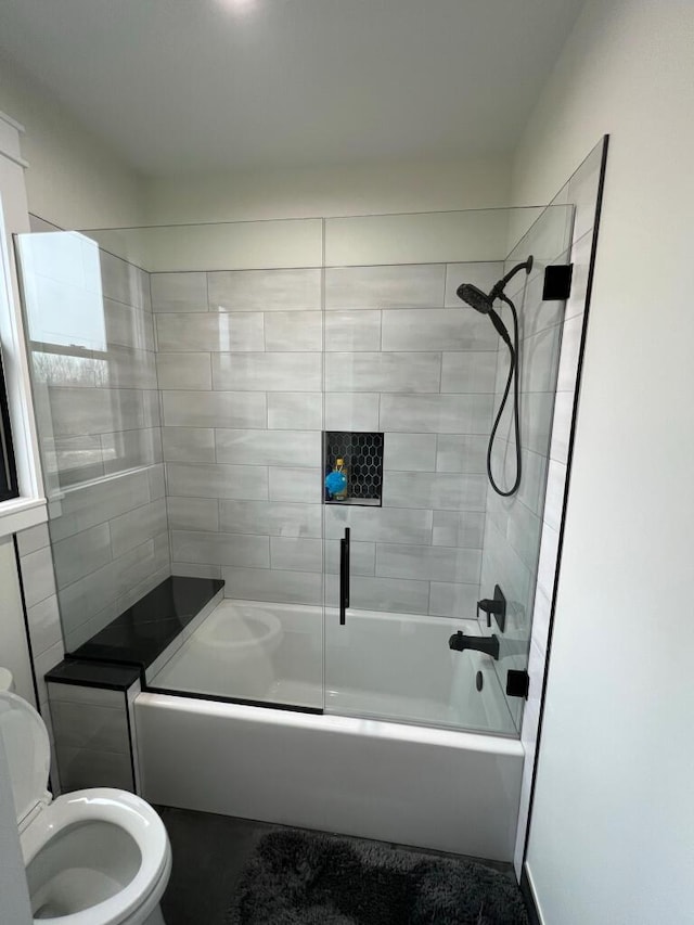 bathroom with toilet and bath / shower combo with glass door