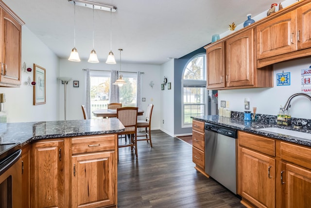 kitchen featuring decorative light fixtures, sink, dark hardwood / wood-style floors, dark stone countertops, and stainless steel appliances