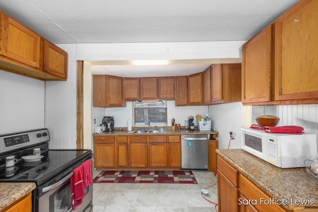 kitchen with a textured ceiling, stainless steel appliances, and sink