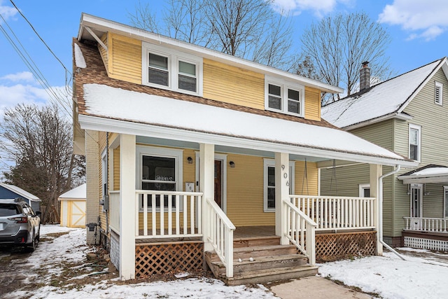 view of front of house featuring a porch and a storage shed