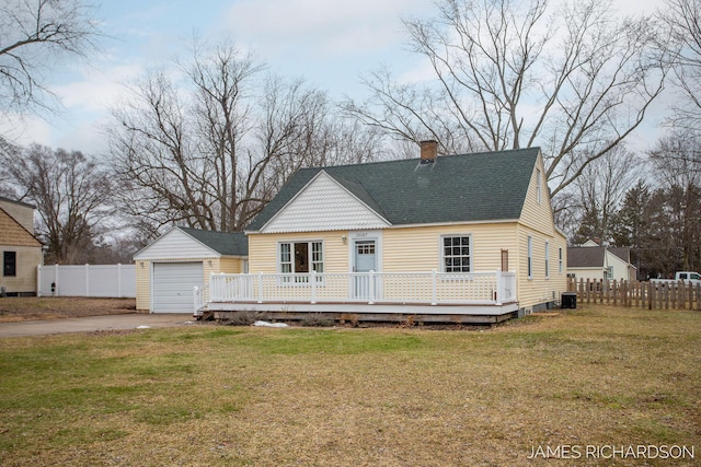 view of front of house featuring a deck, an outdoor structure, fence, and a front lawn