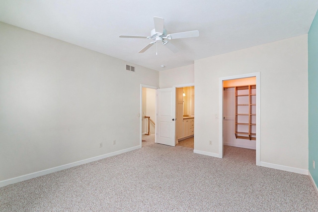 unfurnished bedroom featuring ceiling fan, light colored carpet, a spacious closet, and a closet