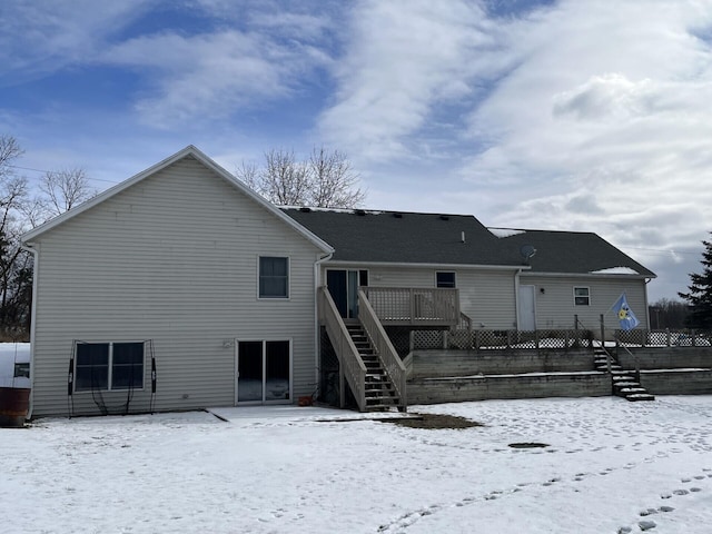 snow covered rear of property with a wooden deck