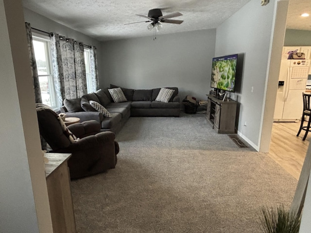 living room featuring ceiling fan, a textured ceiling, and carpet flooring