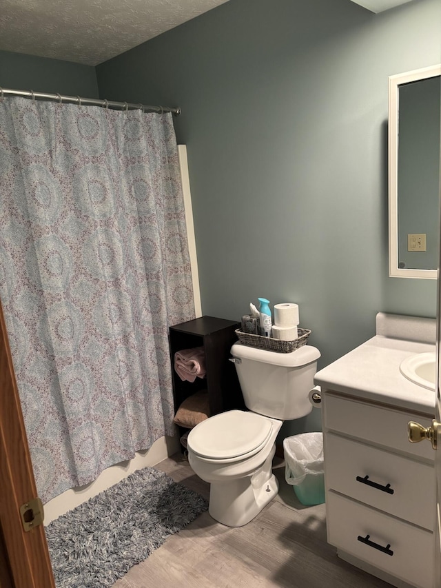 bathroom with toilet, a textured ceiling, hardwood / wood-style flooring, and vanity