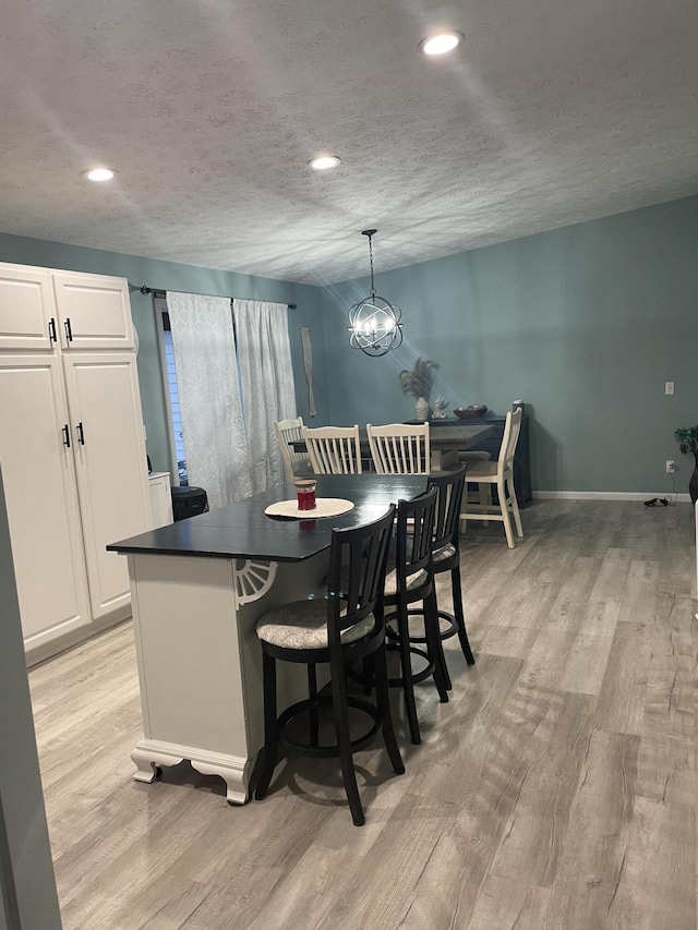 kitchen with decorative light fixtures, white cabinetry, light hardwood / wood-style flooring, and a notable chandelier