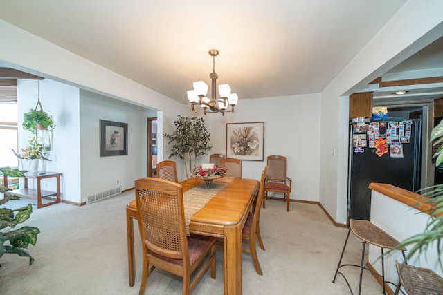 dining space featuring a chandelier and light carpet