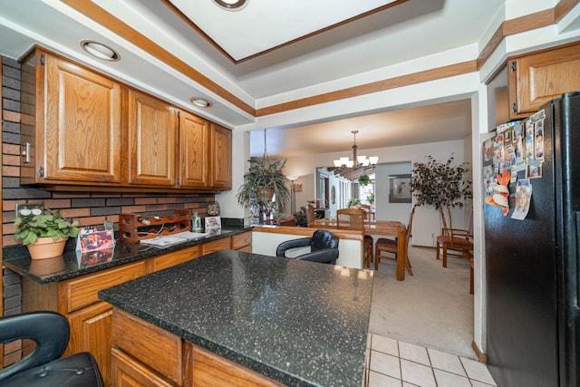 kitchen featuring black refrigerator, decorative light fixtures, decorative backsplash, a notable chandelier, and light carpet