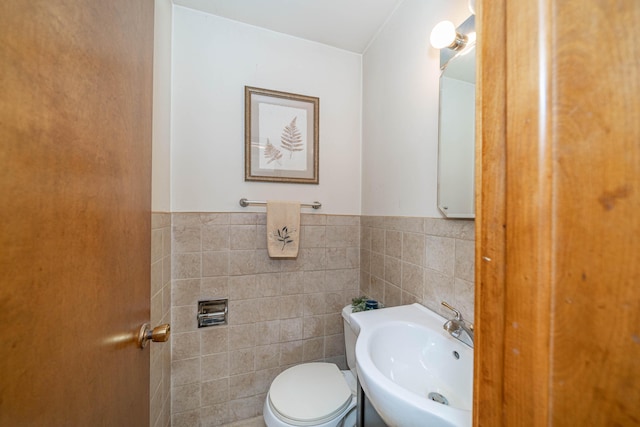 bathroom with sink, tile walls, and toilet