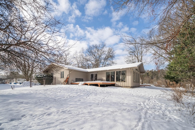 snow covered back of property with a deck