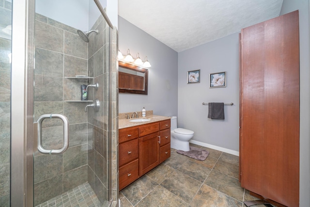 bathroom featuring toilet, vanity, and a shower with door