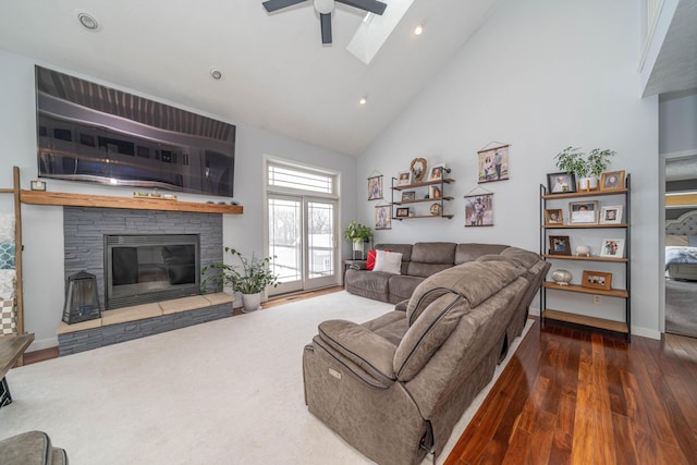 living room featuring high vaulted ceiling, ceiling fan, dark wood-type flooring, and a stone fireplace