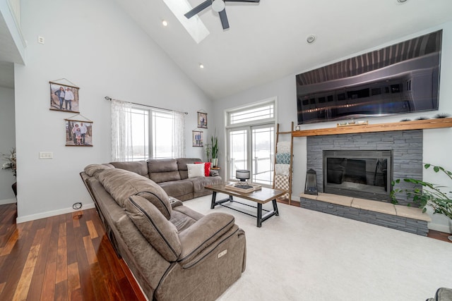 living room with a skylight, hardwood / wood-style flooring, ceiling fan, a fireplace, and high vaulted ceiling