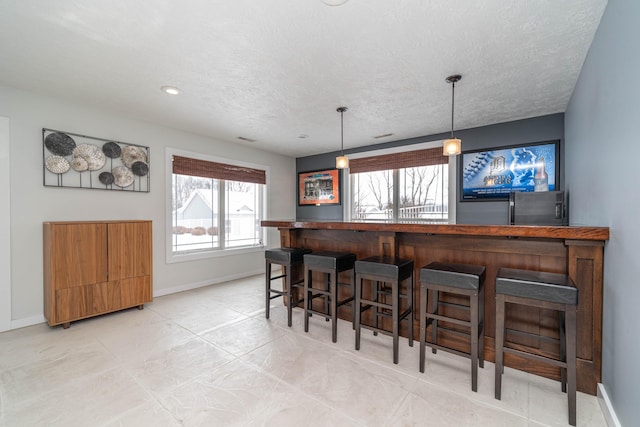 bar featuring hanging light fixtures and a textured ceiling