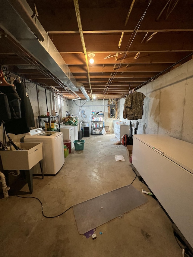 basement featuring sink, washer and clothes dryer, and refrigerator