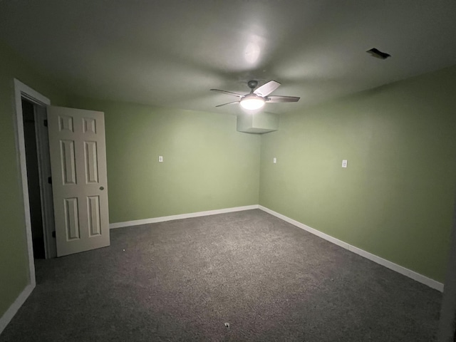 spare room with ceiling fan and dark colored carpet