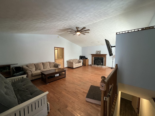 living room featuring wood-type flooring, a textured ceiling, lofted ceiling, and ceiling fan