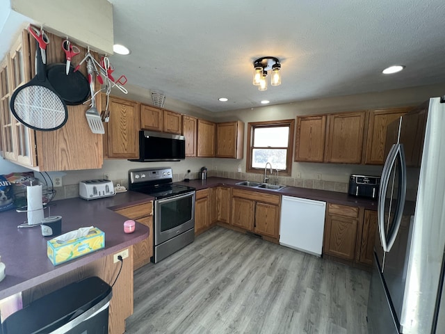 kitchen featuring a textured ceiling, appliances with stainless steel finishes, light wood-type flooring, and sink