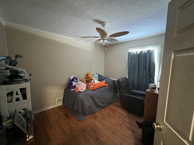 bedroom with a textured ceiling, dark wood-type flooring, and ceiling fan