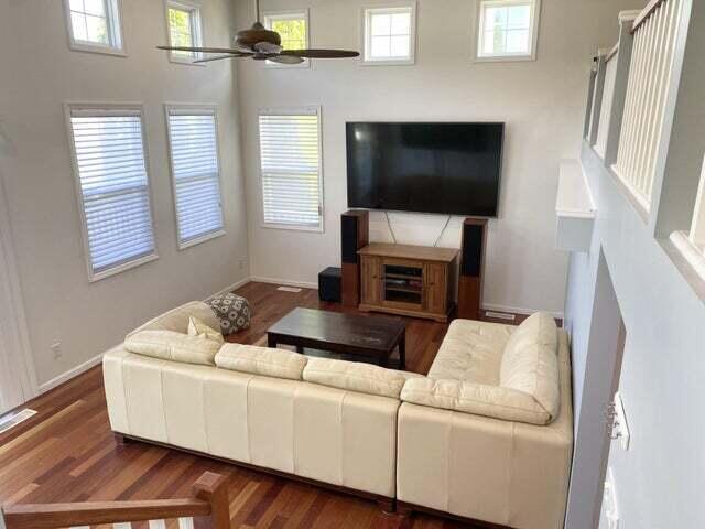 living room featuring ceiling fan, a healthy amount of sunlight, and a high ceiling