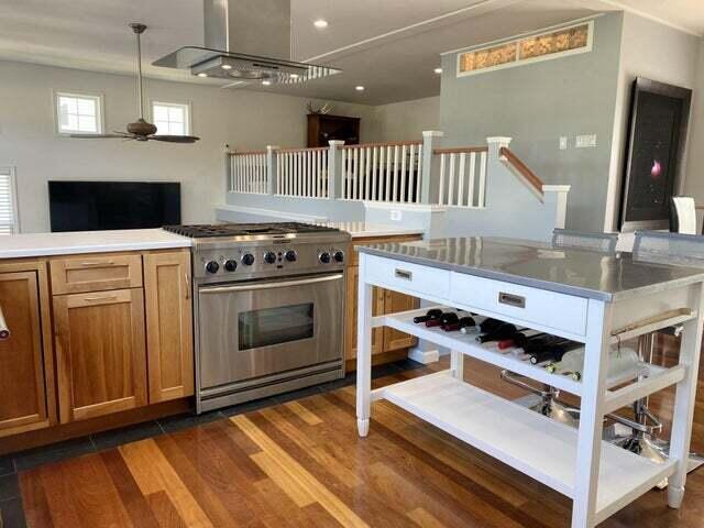 kitchen with ceiling fan, dark hardwood / wood-style floors, range hood, pendant lighting, and high end stove