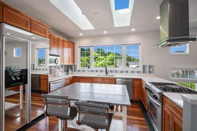 kitchen featuring sink, island exhaust hood, a skylight, dark wood-type flooring, and appliances with stainless steel finishes