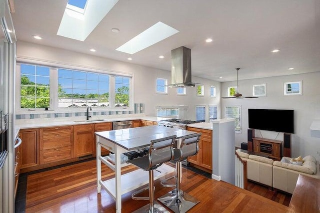 kitchen with ceiling fan, pendant lighting, kitchen peninsula, sink, and island range hood