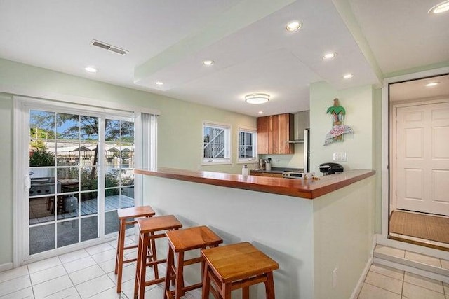 kitchen with a breakfast bar, kitchen peninsula, and light tile patterned flooring