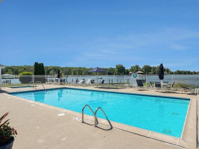 view of pool featuring a water view and a patio area