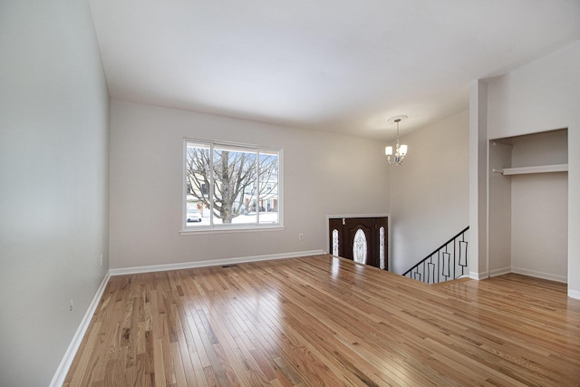 unfurnished room featuring a notable chandelier, vaulted ceiling, and light hardwood / wood-style floors