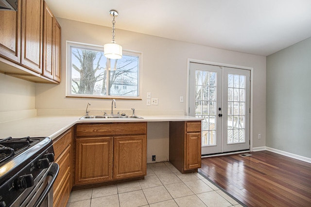 kitchen featuring decorative light fixtures, sink, light tile patterned floors, gas stove, and french doors