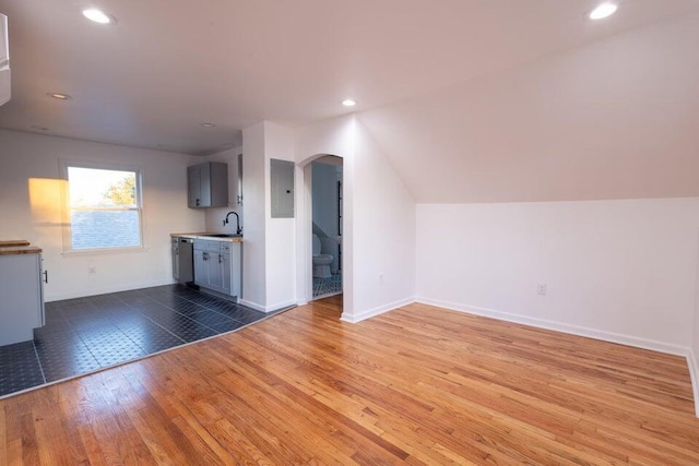 unfurnished living room featuring sink, electric panel, dark hardwood / wood-style flooring, and lofted ceiling