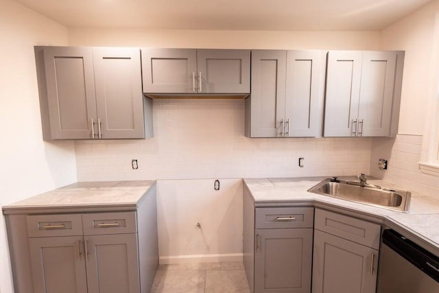 kitchen featuring gray cabinets, light tile patterned floors, stainless steel dishwasher, and sink