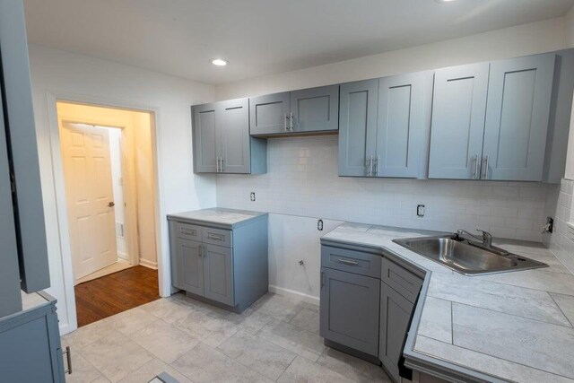 kitchen with decorative backsplash, sink, tile countertops, and gray cabinets