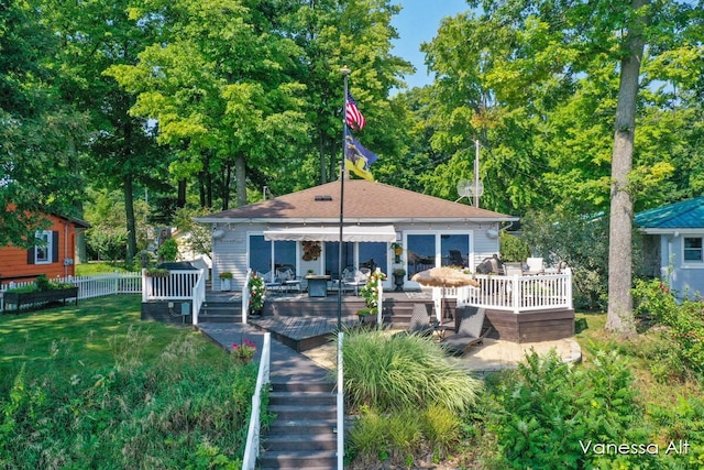 rear view of house featuring a deck and a lawn