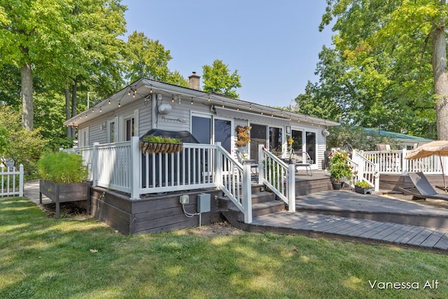 view of front facade with a wooden deck and a front yard