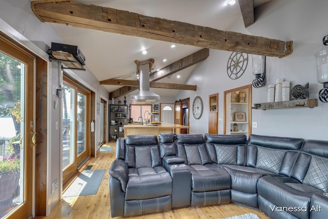 living room with sink, plenty of natural light, lofted ceiling with beams, and light hardwood / wood-style floors