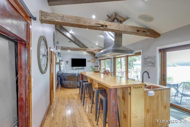 kitchen with sink, light hardwood / wood-style flooring, a kitchen breakfast bar, lofted ceiling with beams, and island exhaust hood