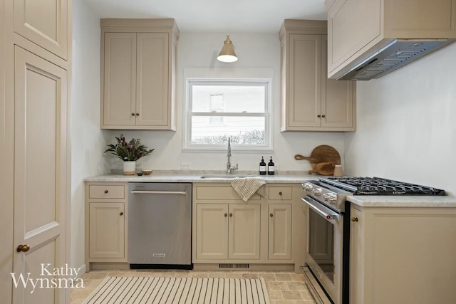 kitchen featuring stainless steel appliances, wall chimney exhaust hood, cream cabinets, and sink